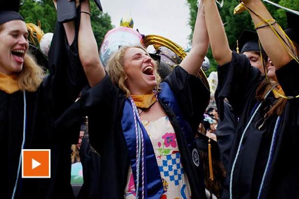 A grad jumps in celebration front of the Rotunda